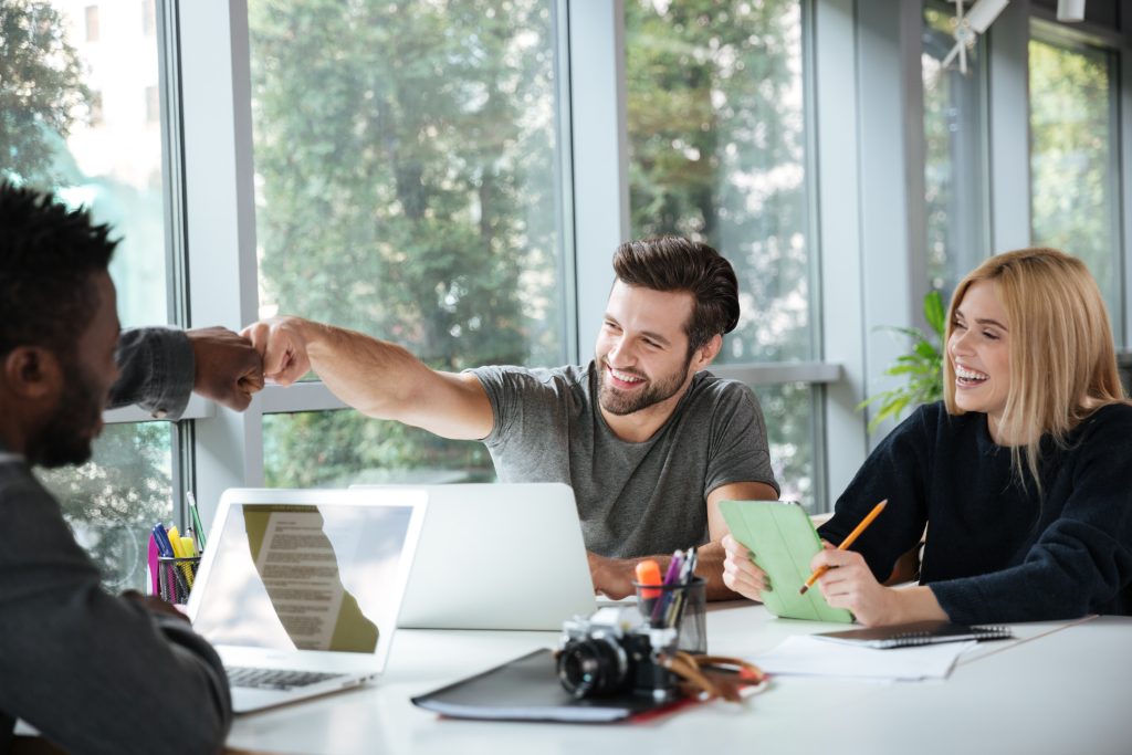 Smiling young colleagues sitting in accountant office coworking
